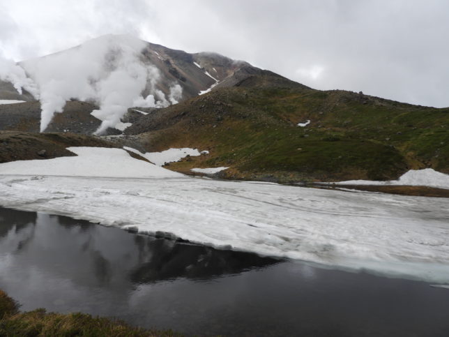 姿見の池から見た山頂、池は雪に覆われていた。右の尾根が登山道